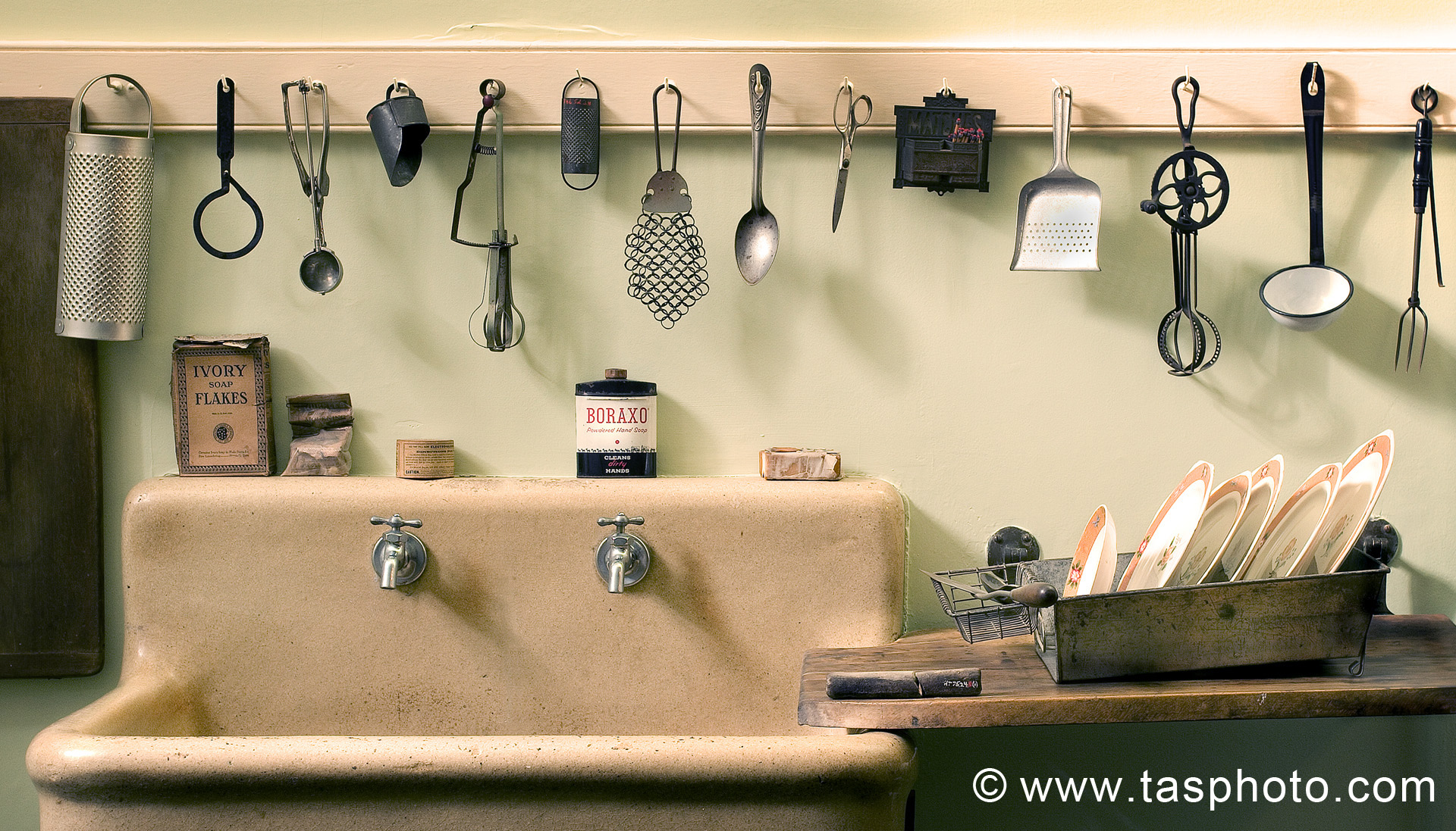 Kitchen sink with vintage utensils hanging above.